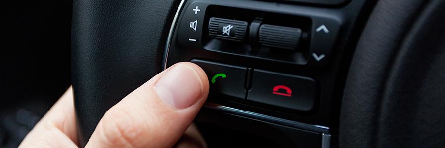 A thumb clicking the dial button on a steering wheel